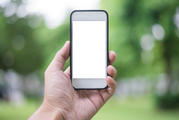 Close-up hand van een man die een smartphone gebruikt in een groen park Mockup van een leeg scherm van een smartphone