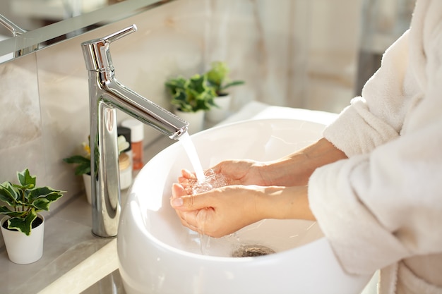 Фото Крупный план. мытье рук. светлая ванная, современный интерьер. халат. домашняя гигиена. фото высокого качества