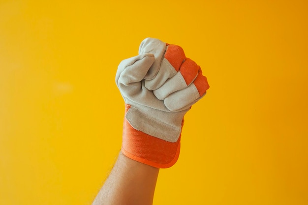 Close-up of hand wearing gloves against yellow background