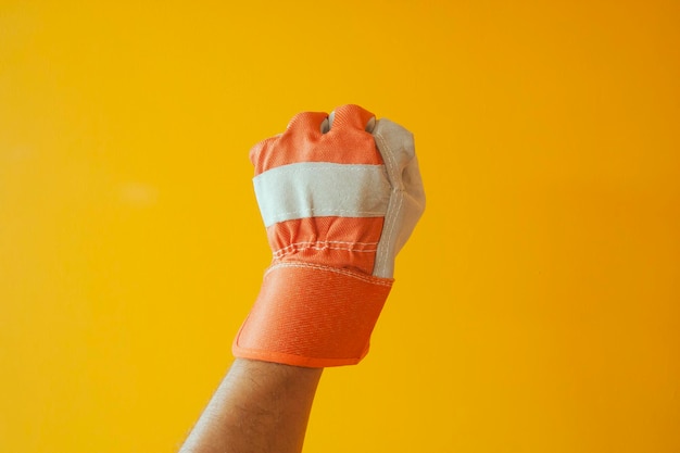 Foto close-up di una mano che indossa guanti su uno sfondo giallo