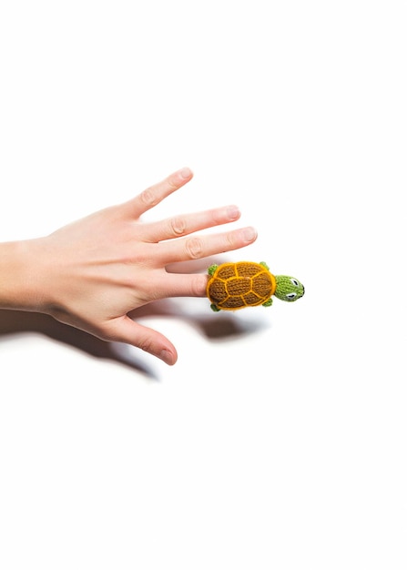 Close-up of hand wearing woolen toy against white background