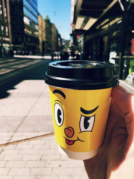 Photo close-up of hand with drink on street in city