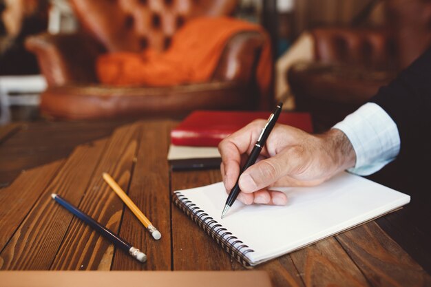 Close-up of hand with pen writing in notebook.