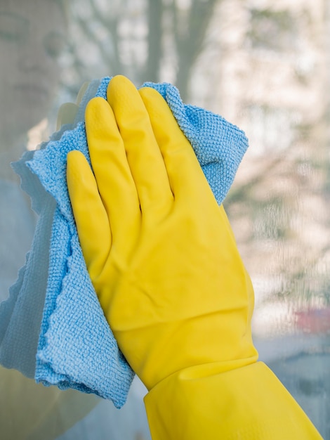 Photo close-up hand with rubber glove cleaning window