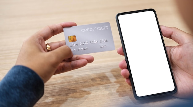 Close up hand of woman shopping online with credit card using smart phone at cafe