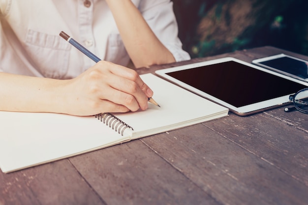 Photo close up hand woman writing notebook on wood table.