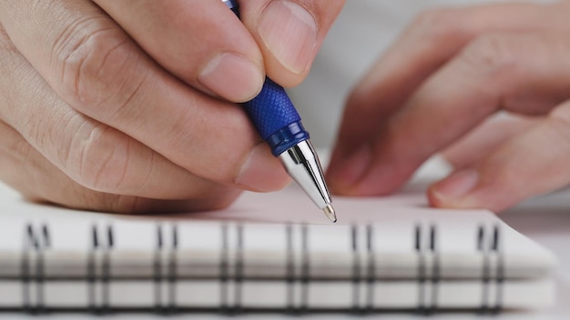 사무실 책상에서 메모, 메모, 목록 작업 계획을 위해 파란색 펜으로 노트북에 손으로 쓴 종이를 닫습니다.