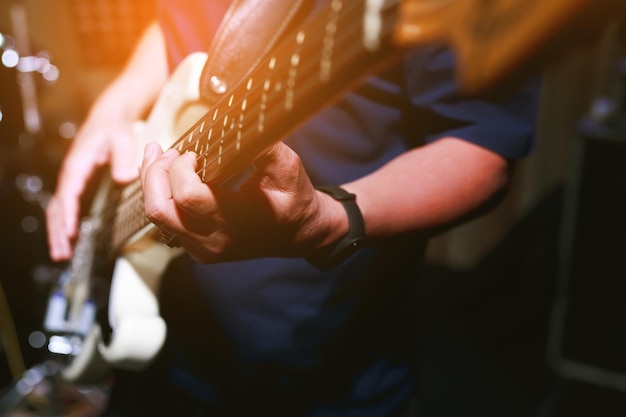 Close up hand young man playing electric guitar at recording\
studio rehearsal base. rock music band.