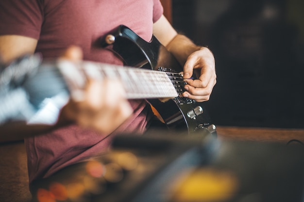 Close up hand of young man playing on a professional, black electric guitar, music instrument, entertainment
