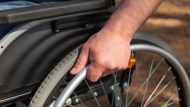 Close up hand of young man steering the wheel of the wheelchair