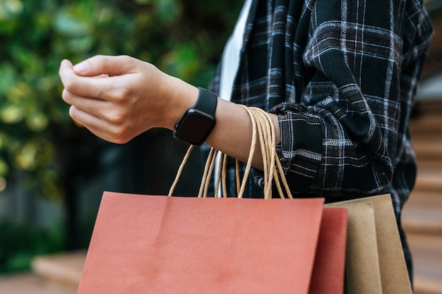 Close up hand of young woman carrying multiple shopping paper\
bag