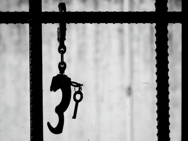 Photo close-up of handcuffs and keys hanging from security bars at prison