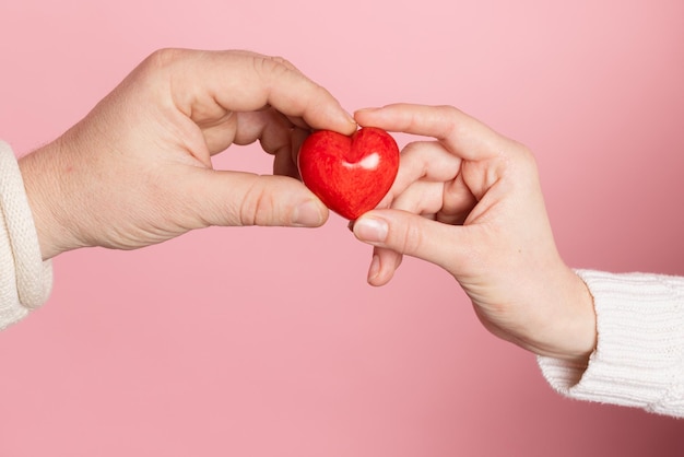 close-up handen die het hart vasthouden op roze achtergrond valentijnsdag concept