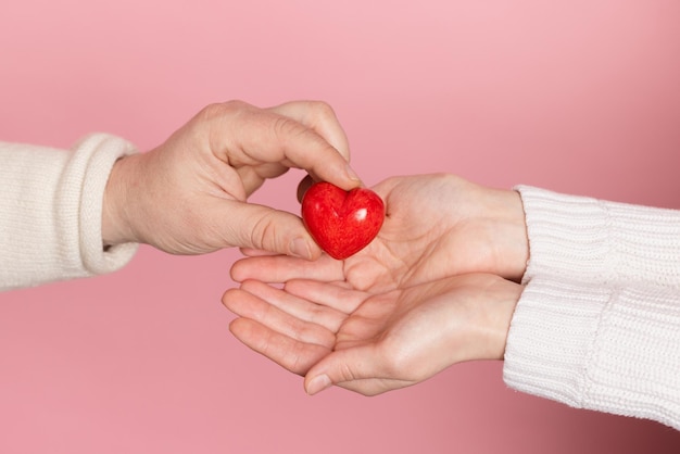 close-up handen die het hart vasthouden op roze achtergrond valentijnsdag concept