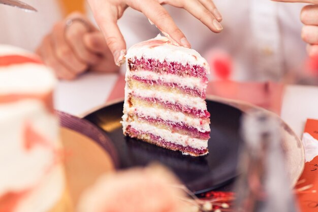 Close-up handen leggen plakje cake in plaat.