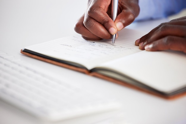 Close-up handen schrijven en notitieboekje op kantoor voor het brainstormen over ideeën en focus op carrièredoelen Afrikaanse man boek en pen voor planningsadministratie of agenda met planningsdagboek en notities