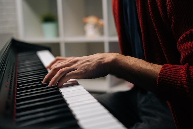 Close-up handen van onherkenbare muzikant die thuis op zachte klassieke muziek speelt