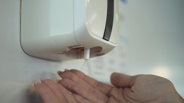 Close-up handen wassen met een automatische alcohol ontsmettingsmiddel dispenser op luchthaven Vrouw hand voor alcoholgel onder auto sanitizer antibacteriële dispenser machine Medische gezondheidszorg Skin Care Concept