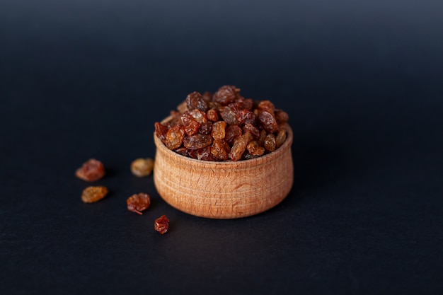 Close-up of handful of brown raisins on wood