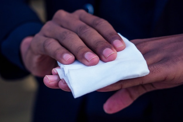 항균 젖은 냅킨 닦는 아프리카계 미국인 남자의 클로즈업 손.