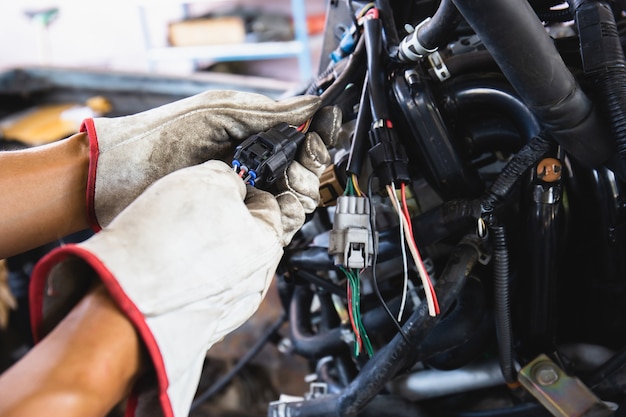 Close up hands of auto mechanic doing car service and maintenance. Car wiring with adapters and connectors changing.