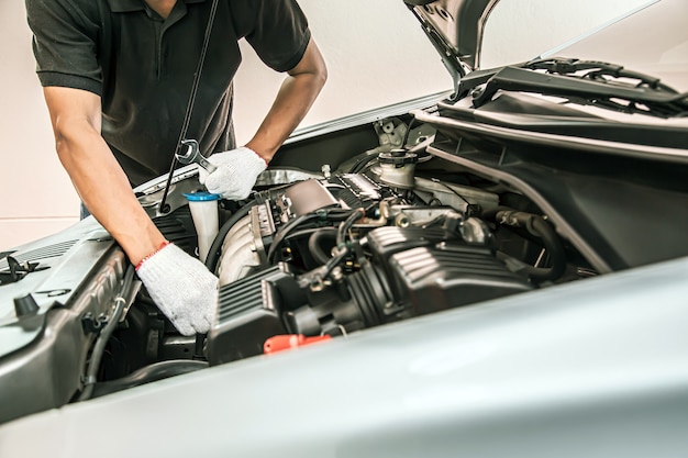 Close-up hands of auto mechanic using the wrench to maintenance car engine.