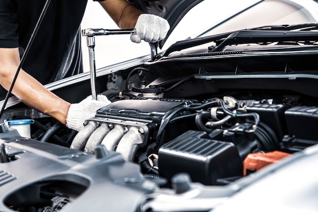 Photo close-up hands of auto mechanic using the wrench to maintenance car engine.