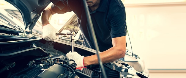 Foto mani ravvicinate del meccanico automatico che utilizzano la chiave per la manutenzione del motore dell'auto.