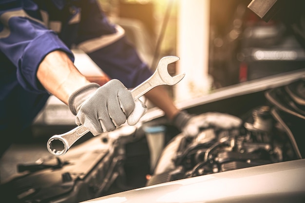 Close-up hands of auto mechanic using the wrench to maintenance car engine.