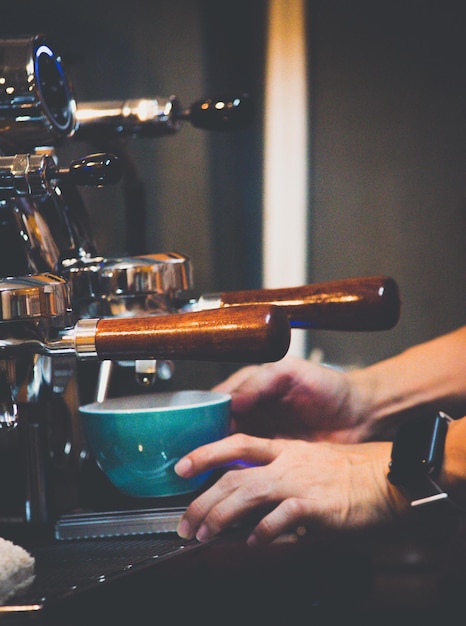 Foto close-up delle mani del barista che fa il caffè nella macchina al caffè