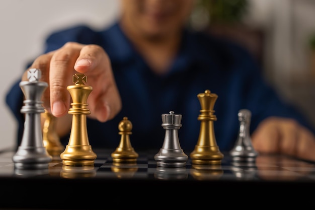 Close up of hands of a business man moving king golden chess to defeat opponent the chess game