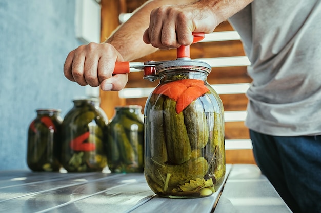 Close up of hands canning cucumbers in a jar