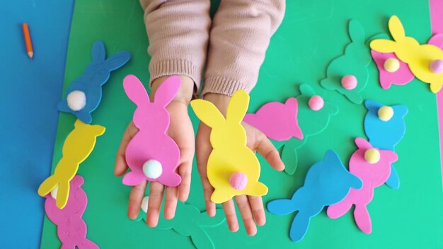 Close up hands child girl holds paper colored garland Easter bunny Cute childrens crafts