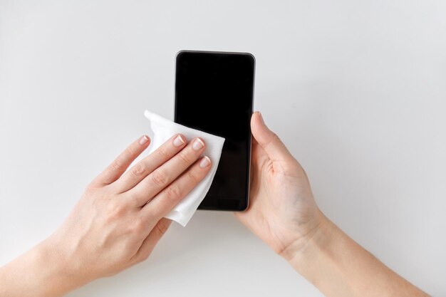 close up of hands cleaning smartphone with tissue