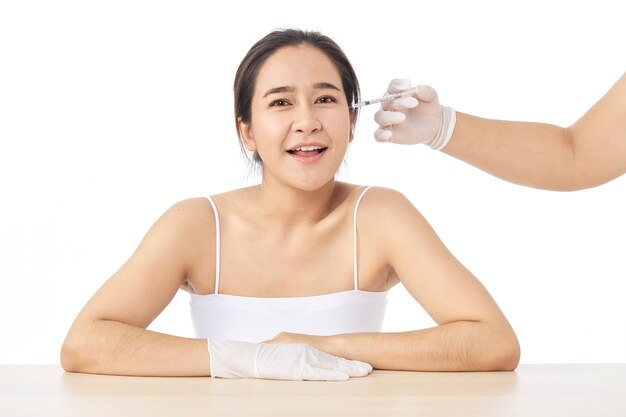 Close up of hands of cosmetologist making botox injection in female face.