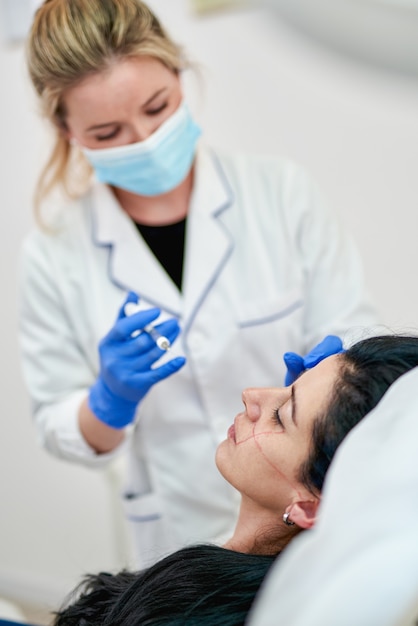 Close up of hands of cosmetologist making botox injection