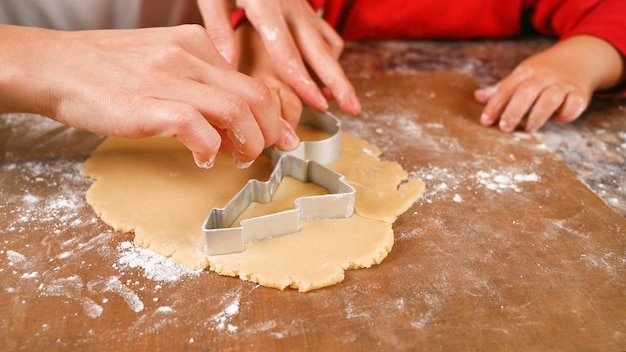 Chiuda in su delle mani che tagliano i biscotti di doug