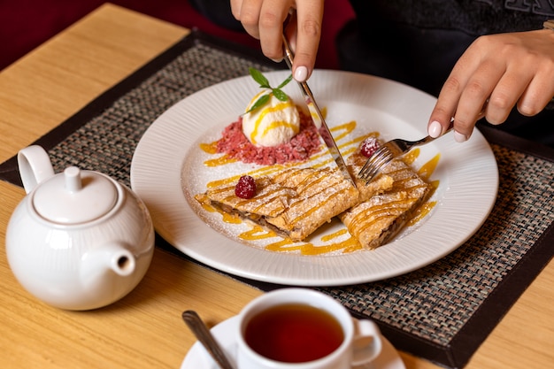 Close up on hands cutting dessert and teapot