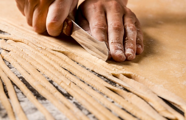 Photo close-up hands cutting dough