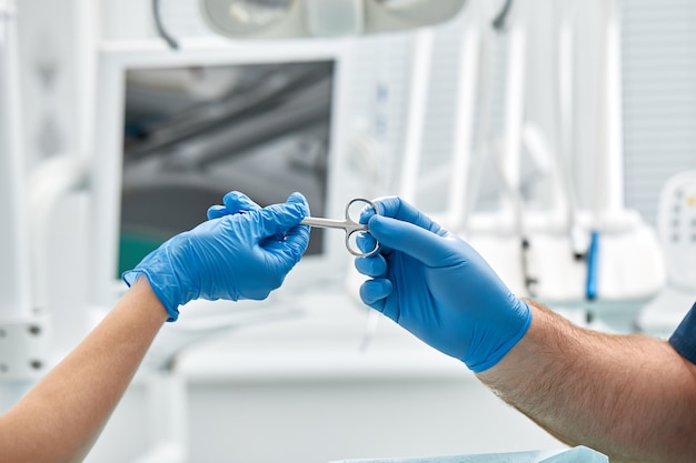 Close-up of the hands of a dentist and nurse surgeon over an operating room during a dental implant operation.