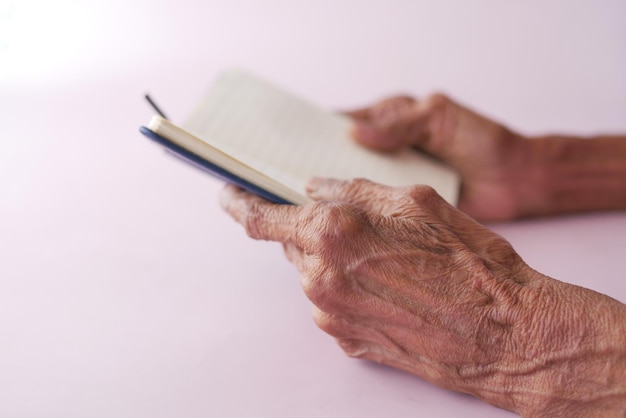 Close up of hands of a elderly person holding a notepad