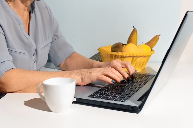 Close-up hands elderly woman typing on laptop