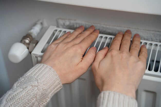 Foto chiudere le mani che si scaldano sul riscaldatore