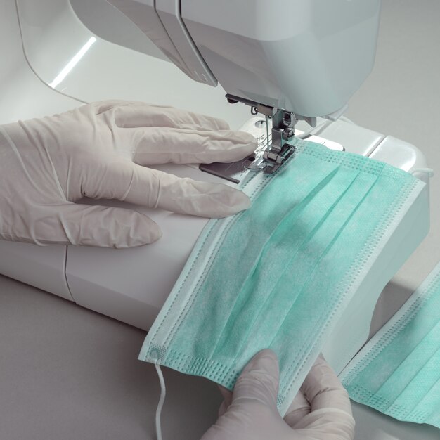 Close up on hands in gloves making medical protective masks