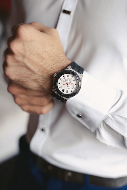 Close-up hands of the groom  with a clock