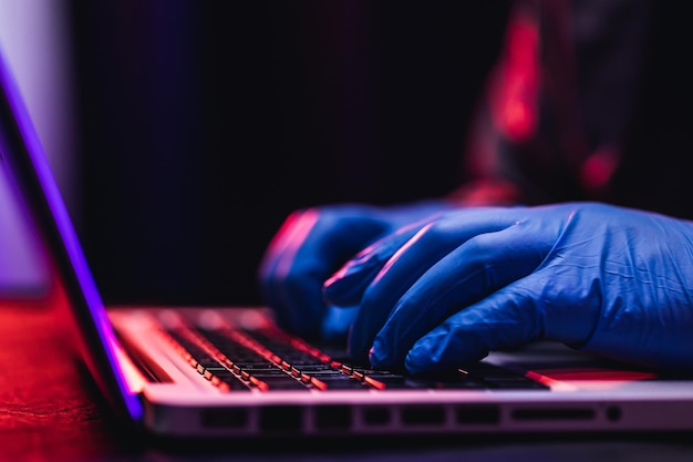 Close up hands hackers. hacking to steal important information.\
use a computer to release malware viruses ransom and harass\
organizations. he sitting in the dark room with neon light