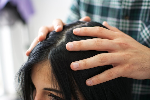 close up of hands of hairdresser making hairstyle for customer