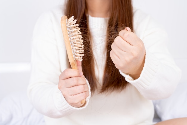 Close up hands holding comb with hair fall problem