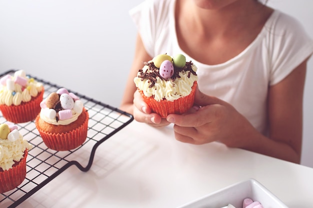 Photo close-up of hands holding cupcake on table