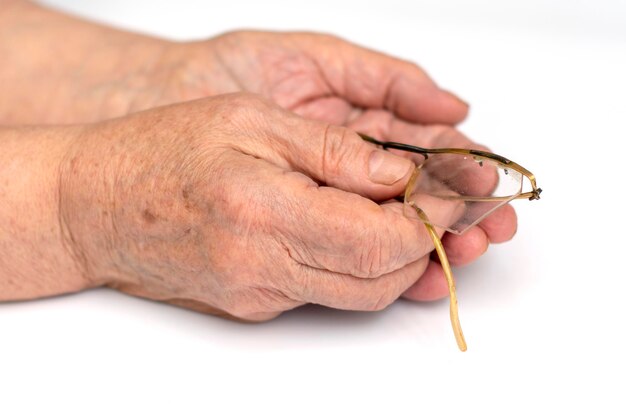 Close-up of hands holding eyeglasses against white background